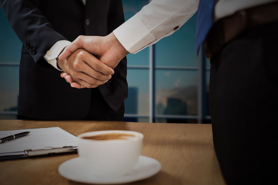 企業同士の商談で握手するビジネスパーソン